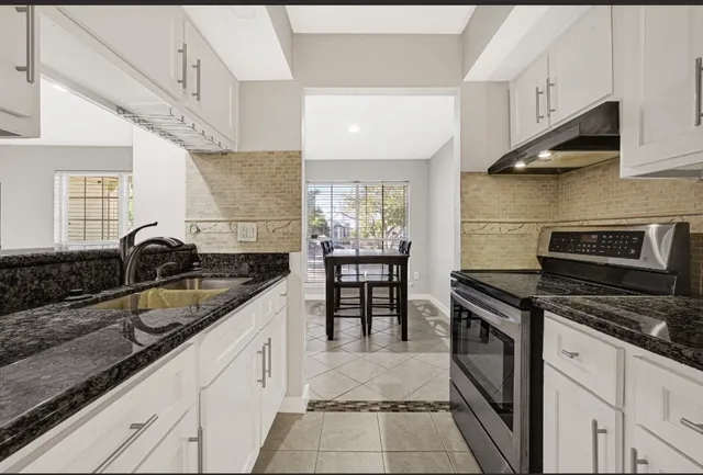 a kitchen with granite countertop a stove and cabinets