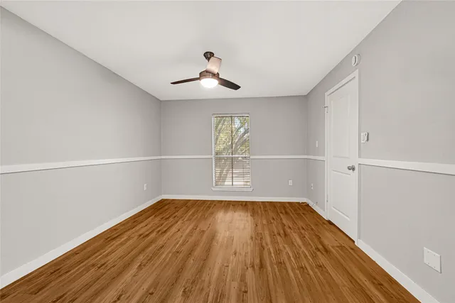 a view of empty room with wooden floor and fan