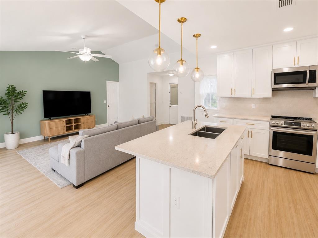 338 Mantis Loop Apopka, FL 32703 - Photo 8 of 11 a kitchen with kitchen island granite countertop a sink a counter top space appliances and cabinets