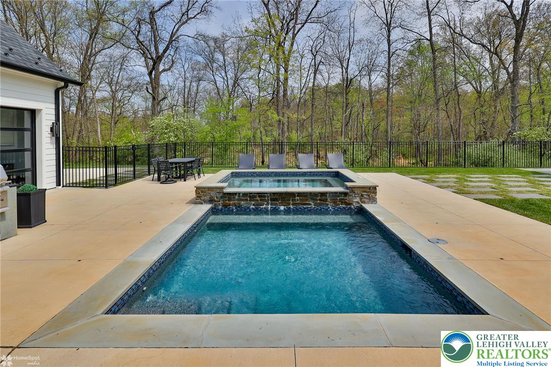 4850 West Hopewell Road Center Valley, PA 18034 - Photo 13 of 96 An inviting backyard oasis offers a sparkling pool and spa, perfect for relaxation and entertaining.