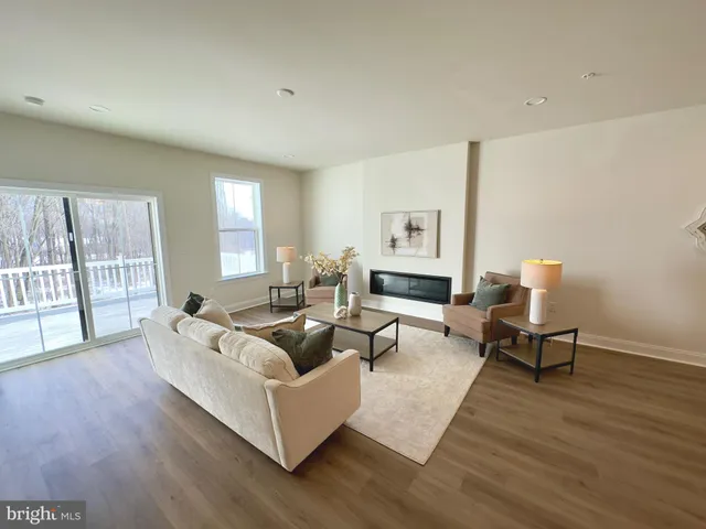 an empty room with wooden floor kitchen view and windows