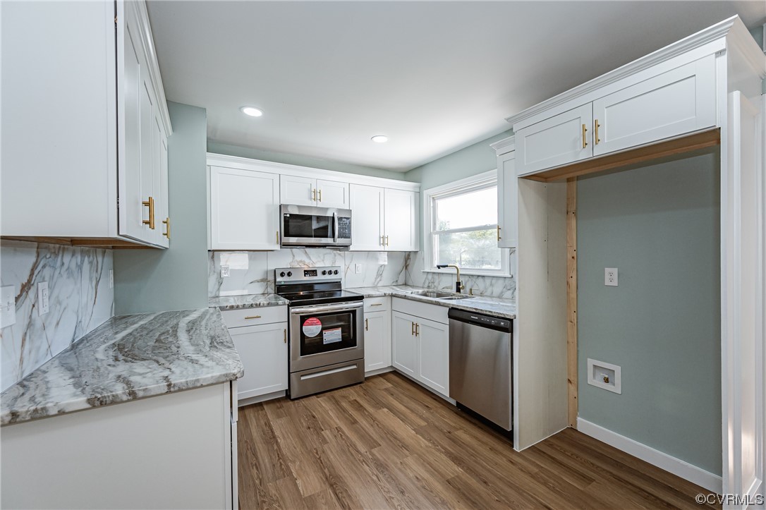 2310 Apollo Road Richmond, VA 23223 - Photo 12 of 22 a kitchen with stainless steel appliances granite countertop white cabinets a sink a stove a refrigerator and microwave with wooden floor