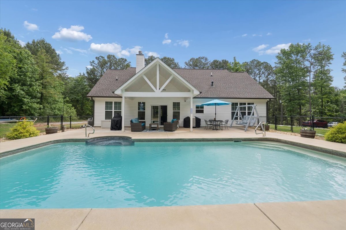 683 Teagle Road Forsyth, GA 31029 - Photo 36 of 50 a view of a swimming pool with lawn chairs and a table and chairs