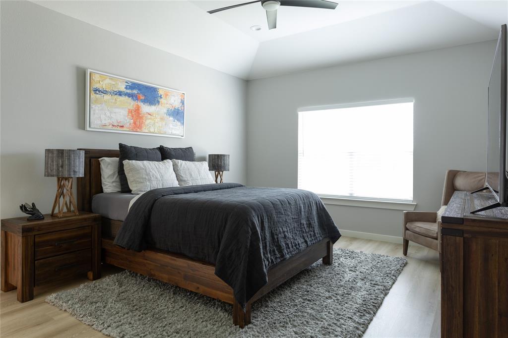 1108 Claude Street Dallas, TX 75203 - Photo 10 of 17 Spacious bedroom featuring a vaulted ceiling with a ceiling fan, light wood-finish flooring, a large window with blinds, and neutral wall tones
