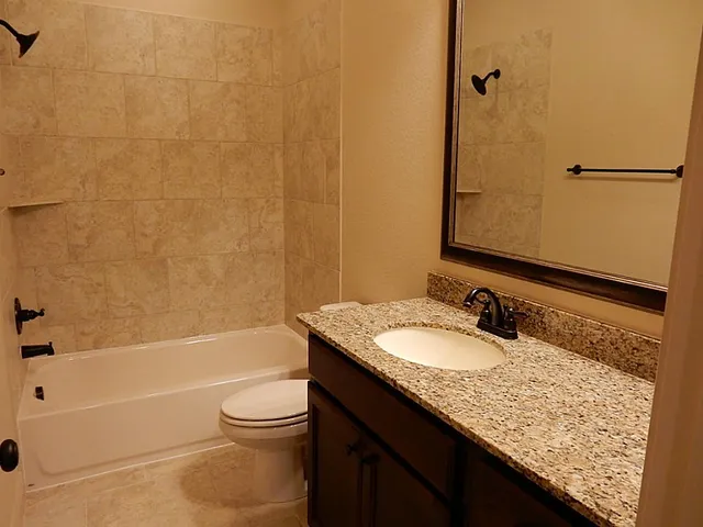 a bathroom with a granite countertop sink toilet and shower