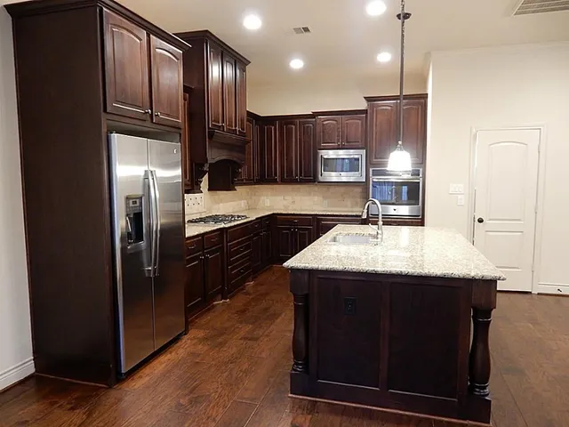 a kitchen with kitchen island stainless steel appliances a sink stove and refrigerator