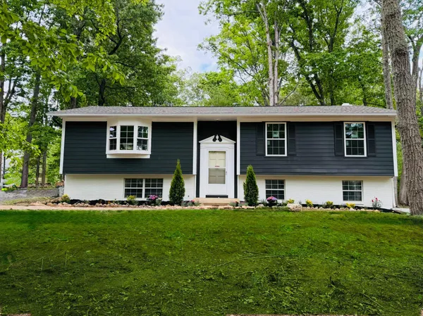 a front view of a house with a garden and trees