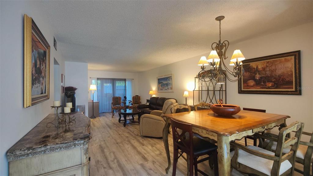 952 Virginia Street, Unit 103 Dunedin, FL 34698 - Photo 13 of 16 a living room with furniture dining table wooden floor and a chandelier