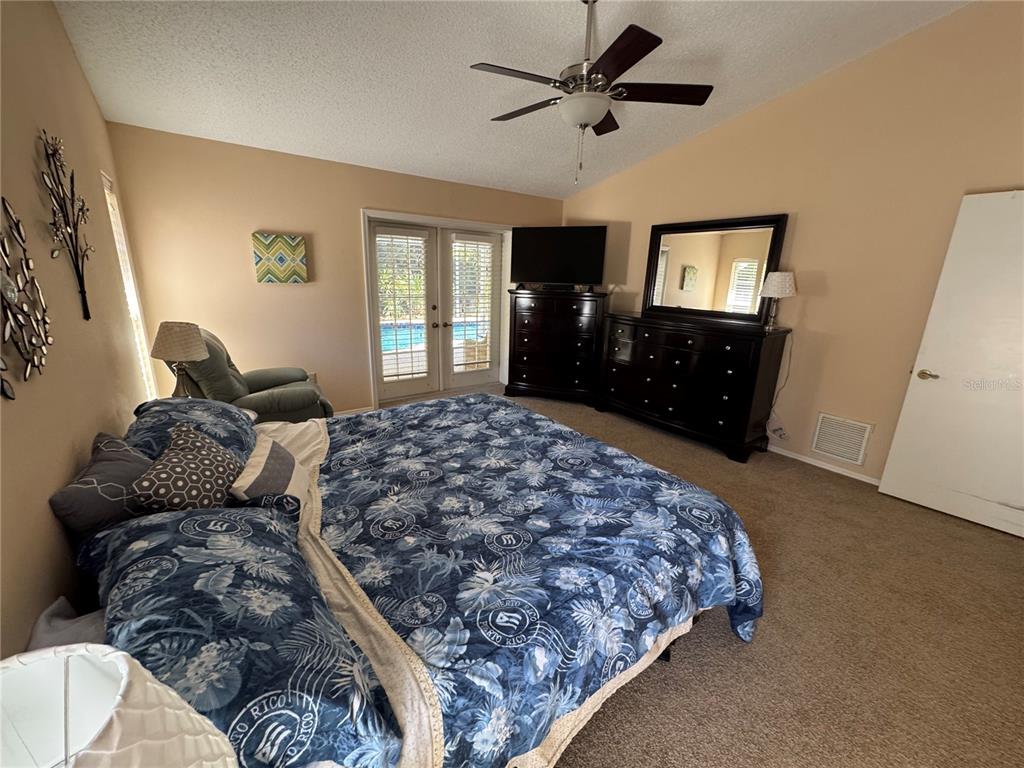 549 Warwick Lane Venice, FL 34293 - Photo 22 of 38 a bedroom with a large bed and a flat tv screen on dresser