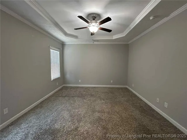 an empty room with chandelier fan and windows