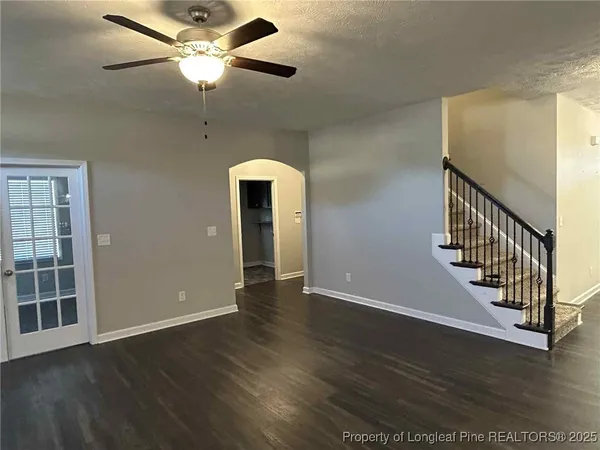 an empty room with wooden floor fan and windows