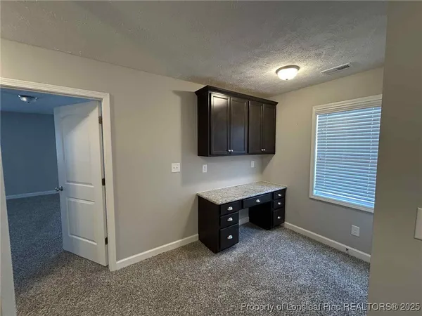 a view of an empty room with kitchen and window