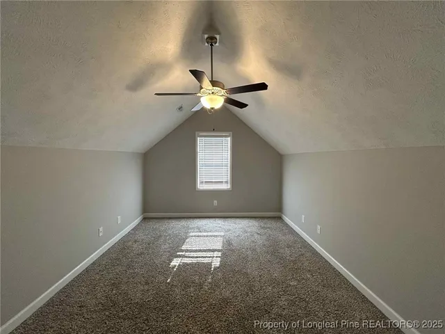 an empty room with a chandelier fan and windows