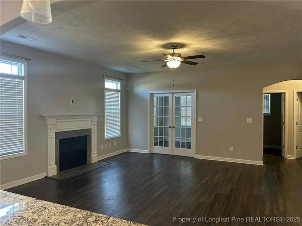 an empty room with wooden floor fireplace and windows