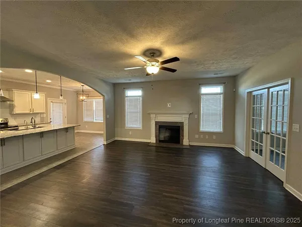 an empty room with wooden floor a ceiling fan and a fireplace