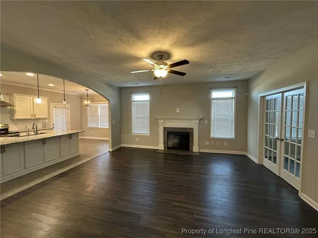 an empty room with wooden floor a ceiling fan and a fireplace