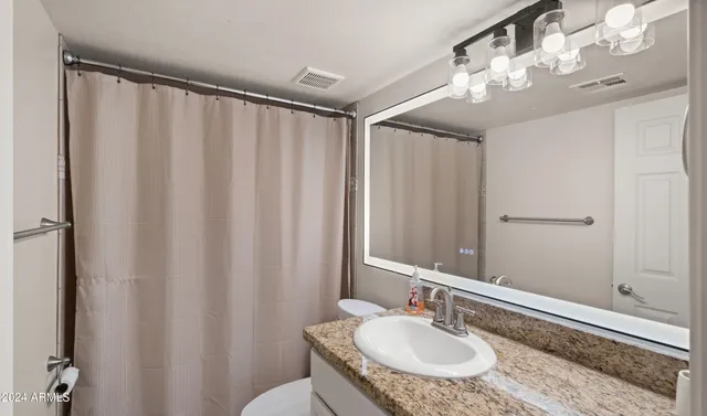 a bathroom with a granite countertop sink and a mirror