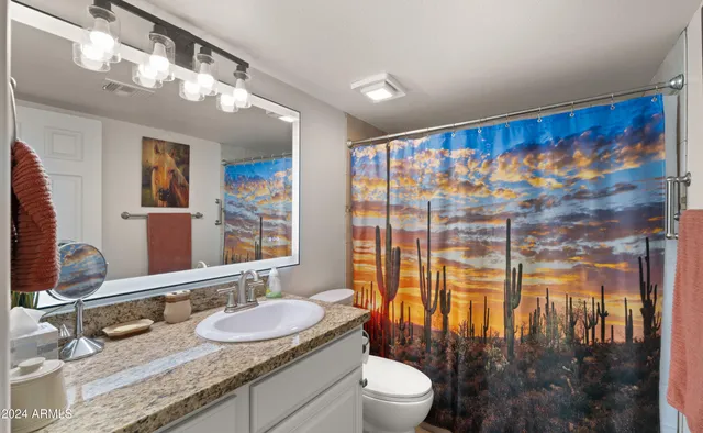 a bathroom with a granite countertop sink mirror vanity and toilet