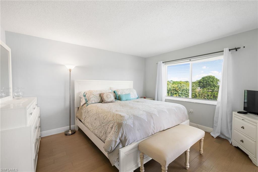 5 High Point Circle West, Unit 307 Naples, FL 34103 - Photo 15 of 31 Bedroom with wood finished floors and a textured ceiling