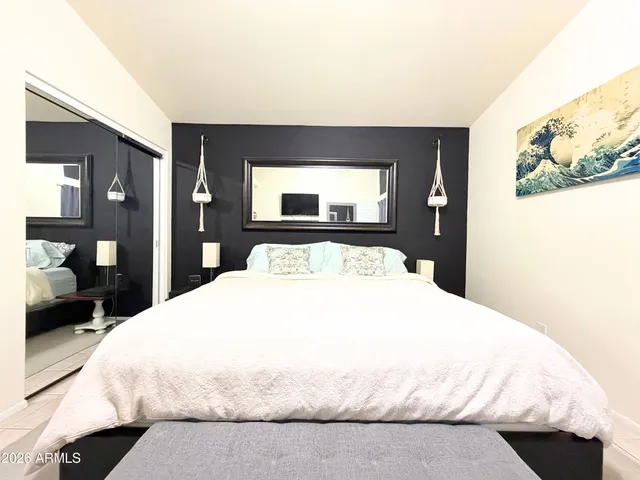 a large white bed in a bedroom next to a window