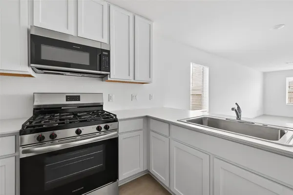a kitchen with stainless steel appliances granite countertop grey cabinets a stove a sink and dishwasher