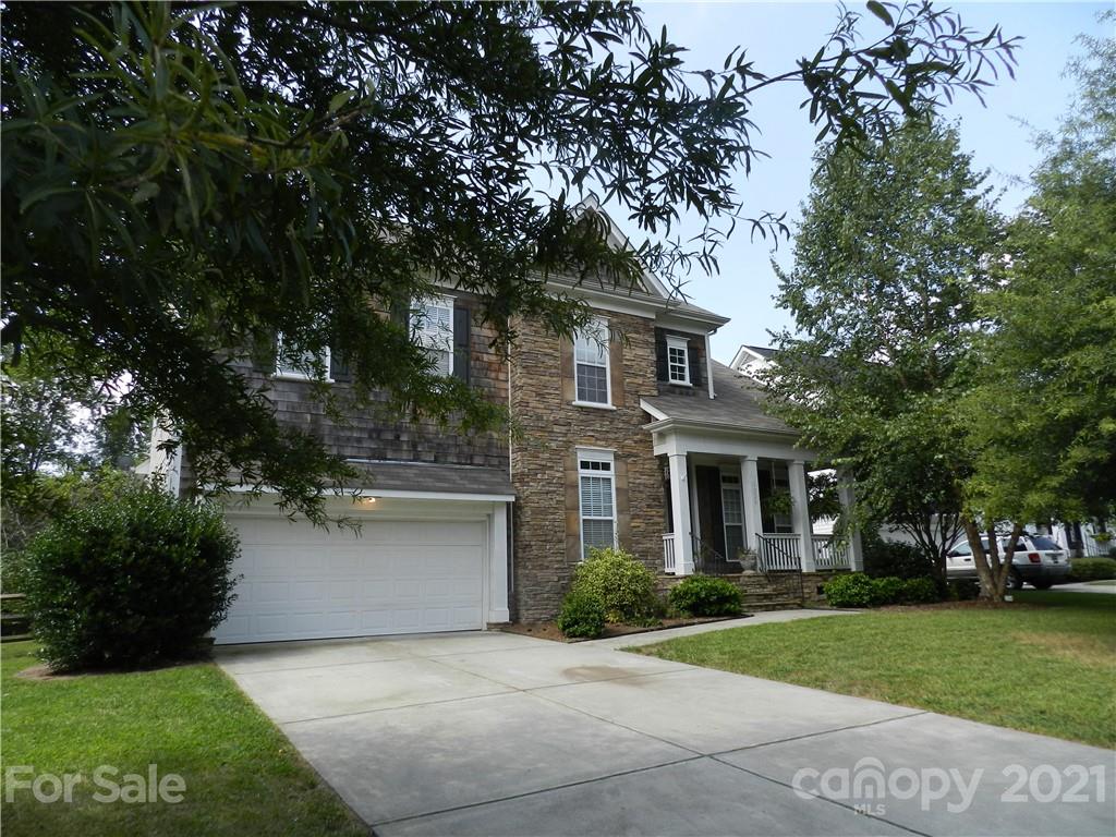 a front view of a house with a garden and tree