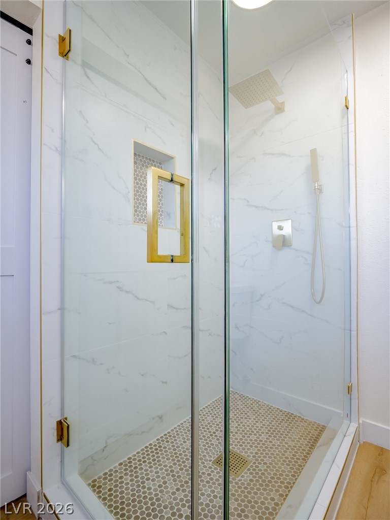 321 Lakehurst Road Las Vegas, NV 89145 - Photo 24 of 33 Floor-to-ceiling marble-patterned tile surrounds this modern walk-in shower with refined gold hardware accents.