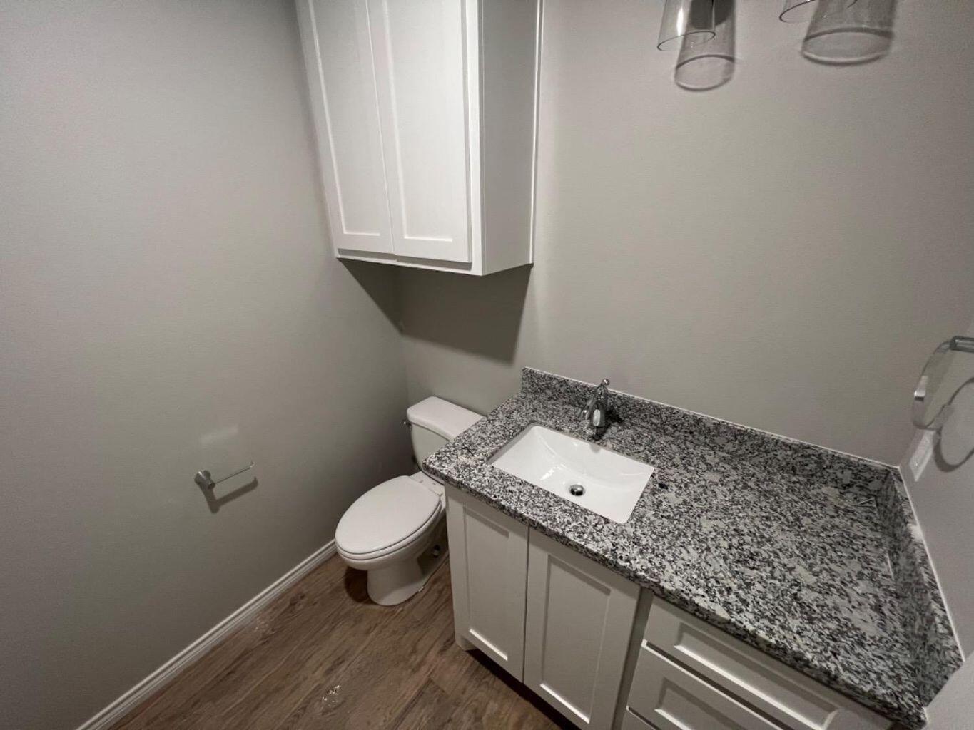 1407 17th Street, Unit A Shallowater, TX 79363 - Photo 15 of 18 a bathroom with a granite countertop sink and a toilet