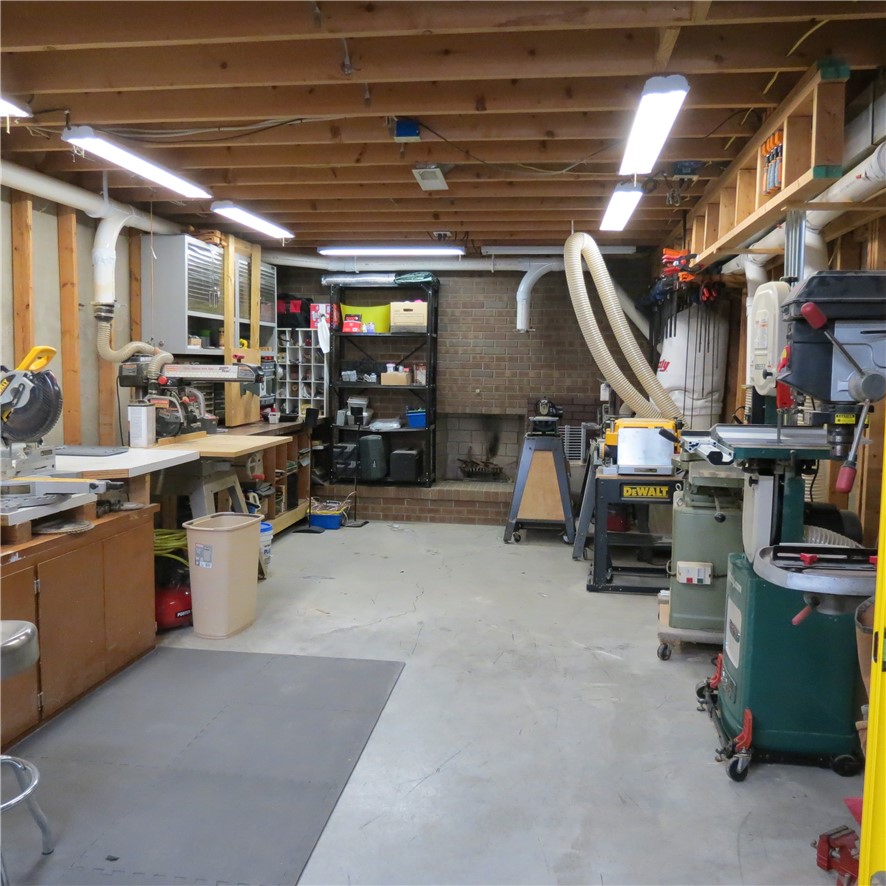 10160 Lochard Road Sidney, OH 45365 - Photo 32 of 41 This spacious workshop features exposed ceiling beams and a brick accent wall, ideal for hobbies and projects.
