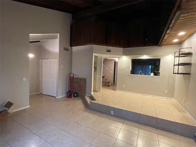 a view of a hallway with stainless steel appliances a refrigerator and a fireplace