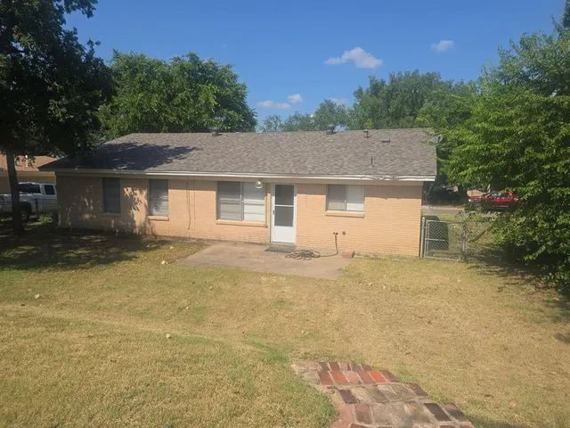 a view of a house with a yard and large tree