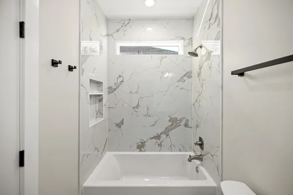 a bathroom with a bathtub shower sink vanity and toilet