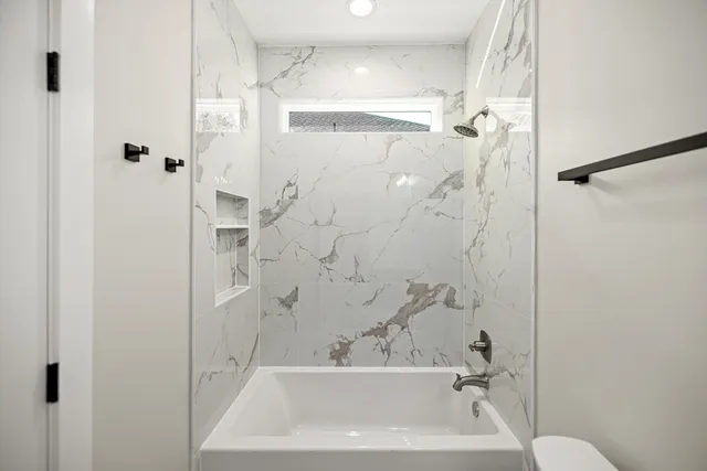 a bathroom with a bathtub shower sink vanity and toilet
