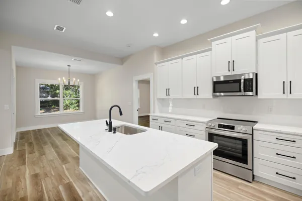 a large kitchen with a center island wooden floor stainless steel appliances and windows