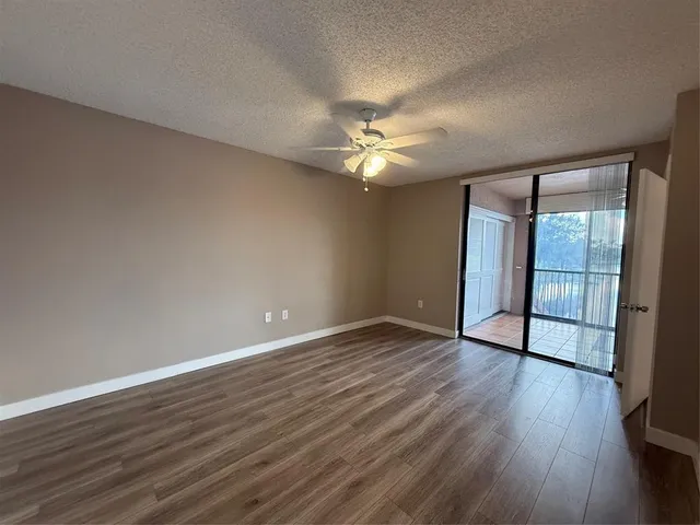 wooden floor in an empty room with a chandelier fan