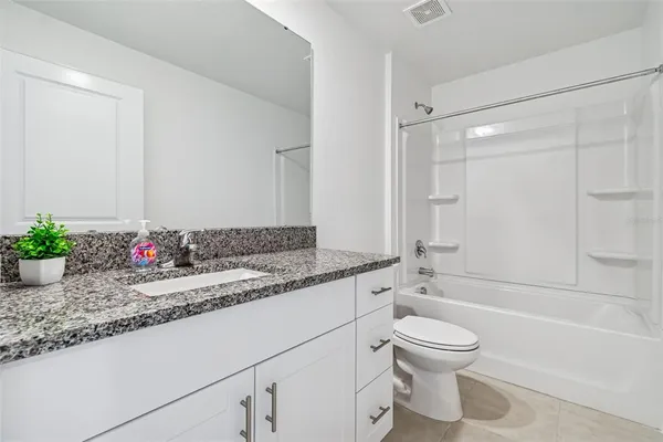 a white bath tub sitting next to a white toilet and vanity