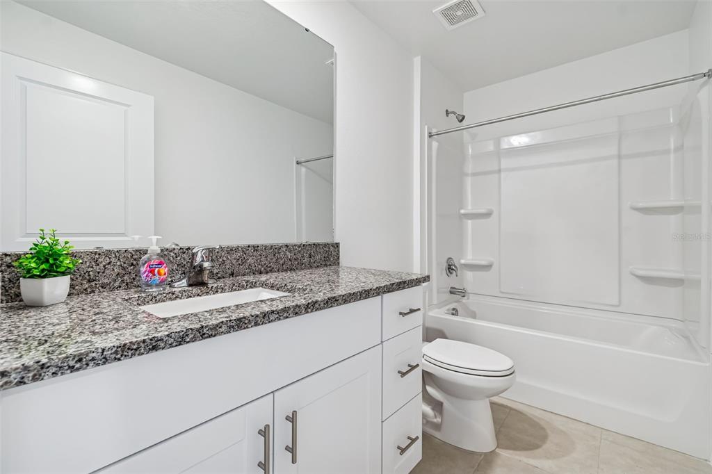 4530 Cozy Condor Court Bartow, FL 33830 - Photo 21 of 35 a bathroom with a granite countertop sink a toilet a mirror and bathtub