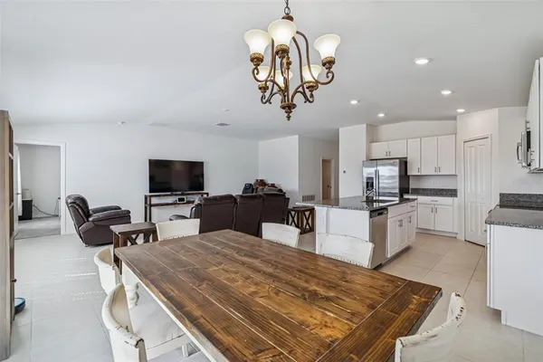 a kitchen view with stainless steel appliances kitchen island granite countertop a sink dishwasher a dining table and chairs with wooden floor