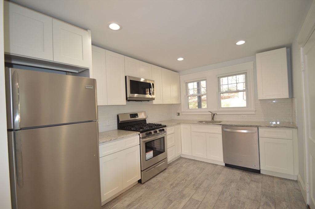 51 Leamington Road, Unit 1 Boston, MA 02135 - Photo 2 of 12 a kitchen with a refrigerator a sink a stove top oven and wooden floor
