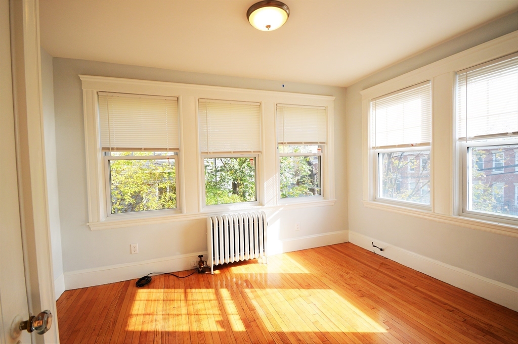 51 Leamington Road, Unit 1 Boston, MA 02135 - Photo 7 of 12 a view of an empty room with wooden floor and a window