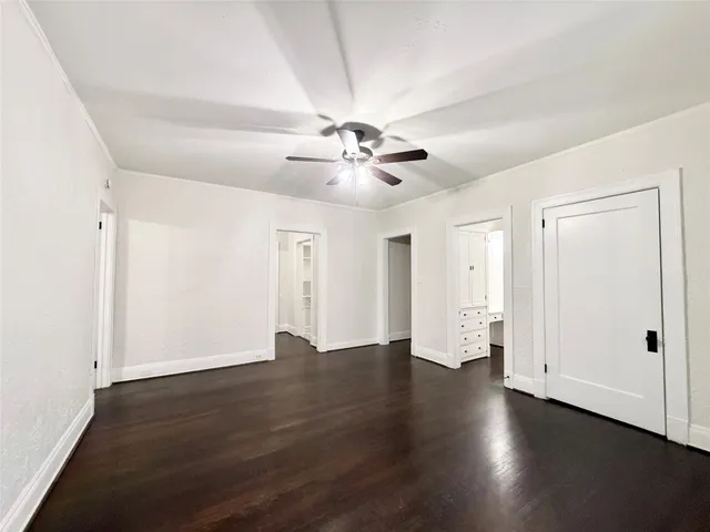 an empty room with wooden floor and ceiling fan