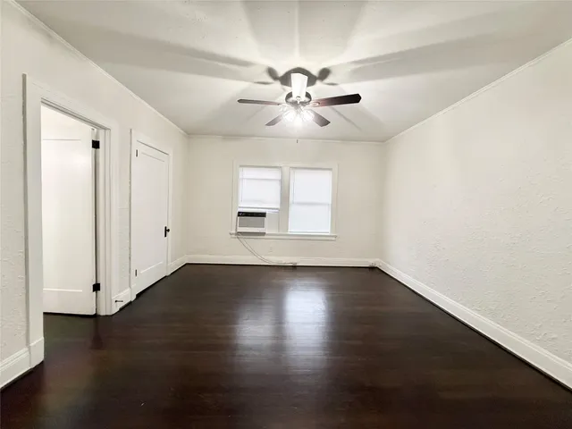 an empty room with wooden floor chandelier fan and windows
