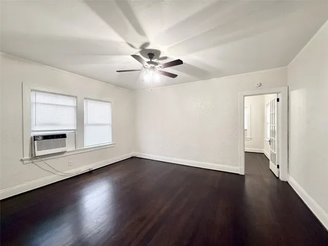 an empty room with wooden floor chandelier fan and windows