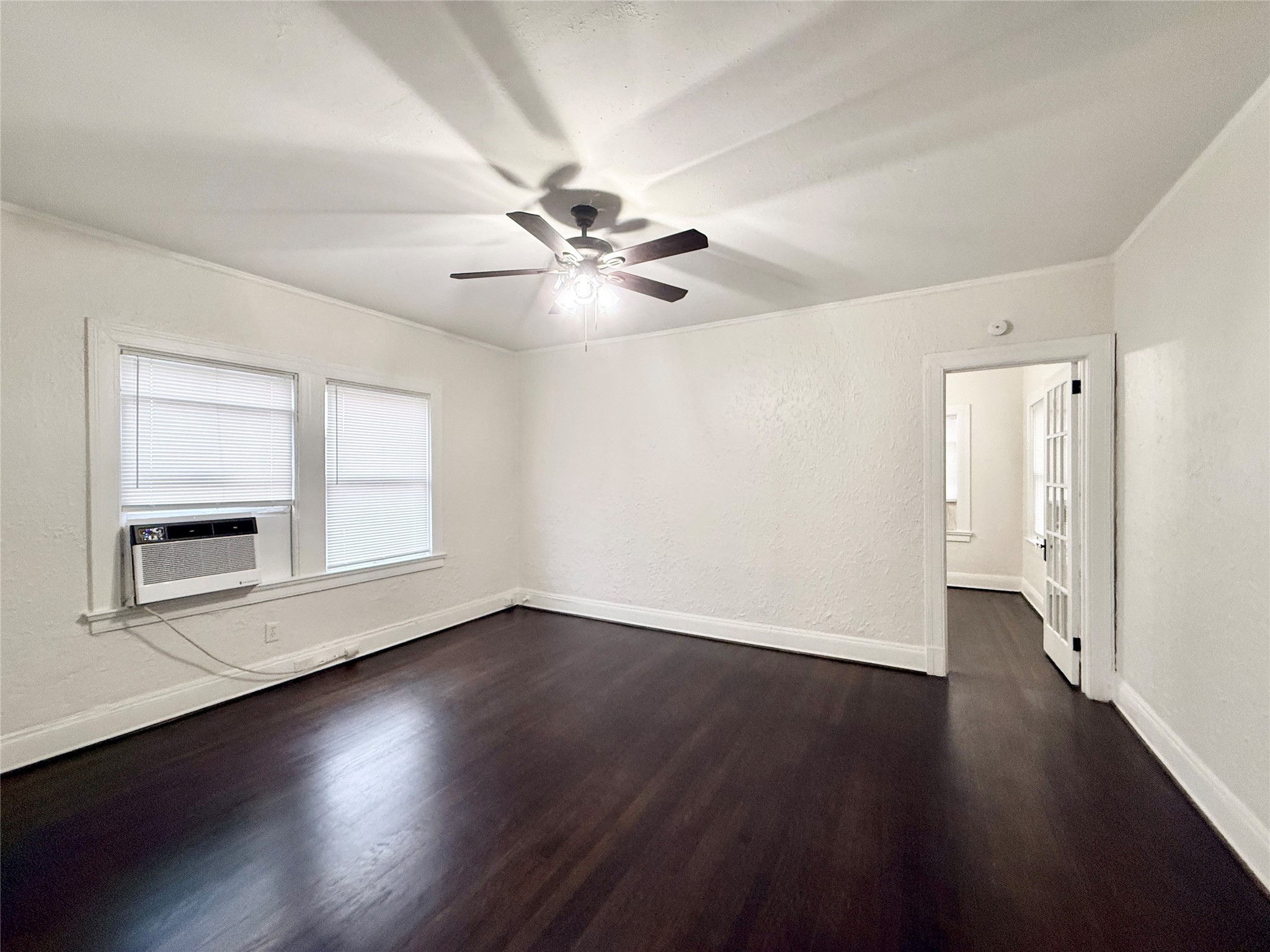 3920 Fannin Street, Unit 103 Houston, TX 77004 - Photo 6 of 24 an empty room with wooden floor chandelier fan and windows