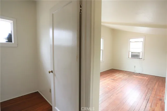 an empty room with wooden floor closet and windows