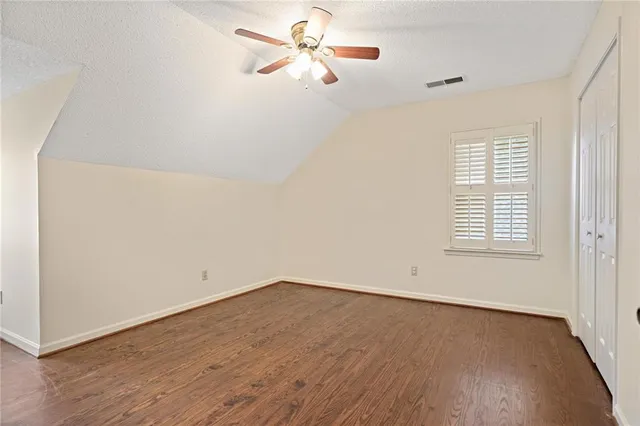 an empty room with wooden floor fan and windows