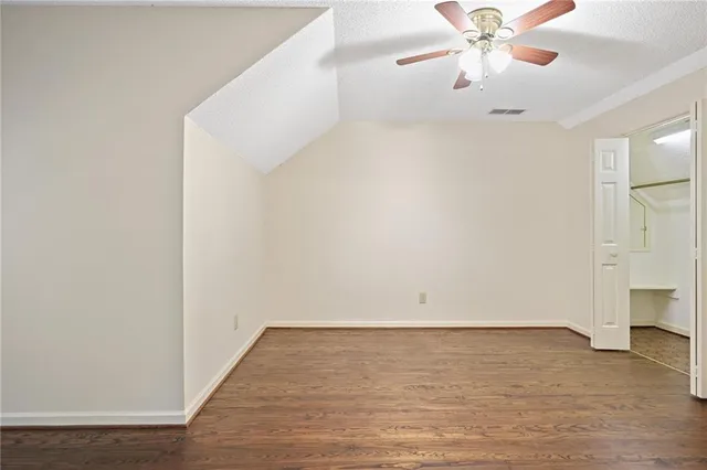 an empty room with wooden floor and chandelier fan