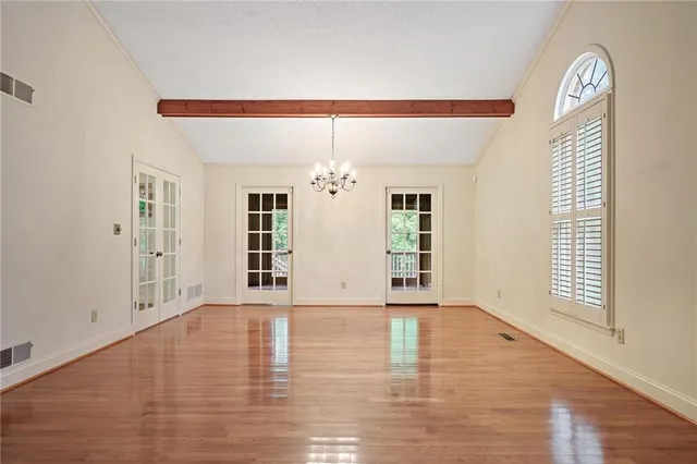 a view of an empty room with window and wooden floor