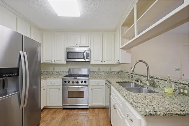 a kitchen with granite countertop a sink stainless steel appliances and cabinets