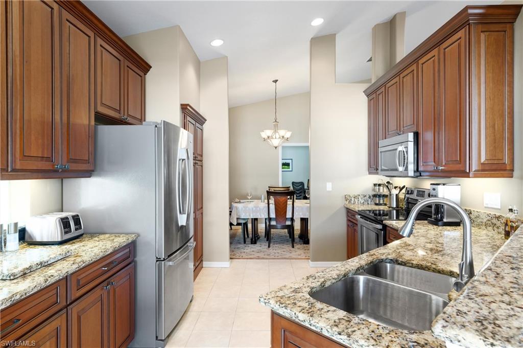 96 Glen Eagle Circle Naples, FL 34104 - Photo 8 of 33 a kitchen with stainless steel appliances granite countertop a sink refrigerator and cabinets